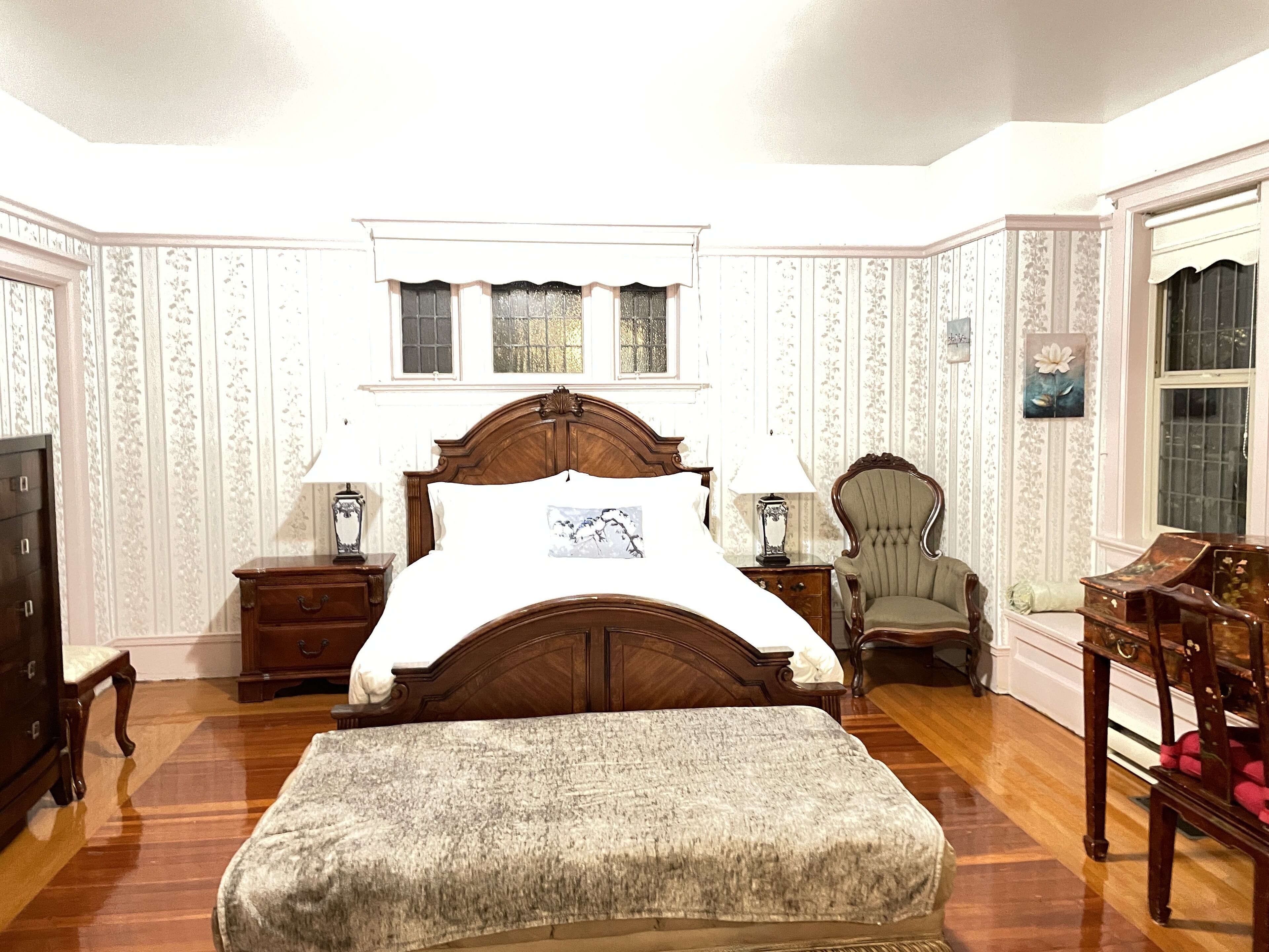 A bedroom with a large bed, two bedside tables, a chair, and a dresser.