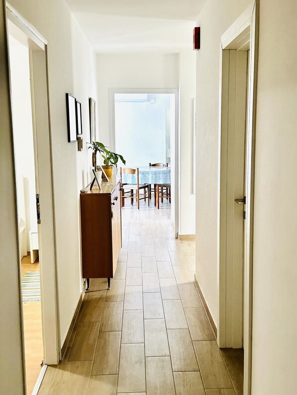 A hallway with a dining area at the end, featuring a table and chairs.