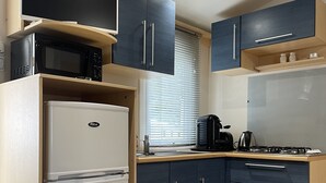 Eine kompakte Küche mit einem weißen Kühlschrank, einer Mikrowelle und einem Herd.