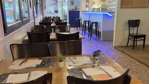 Ein Restaurant mit Holztischen und -stühlen, einer Bar und Blick auf die Straße.