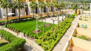 A modern residential building with multiple balconies, a well-maintained lawn, and a mountain view in the background. - Residencial Oropesa - La Concha by Interhome (Oropesa del Mar)
