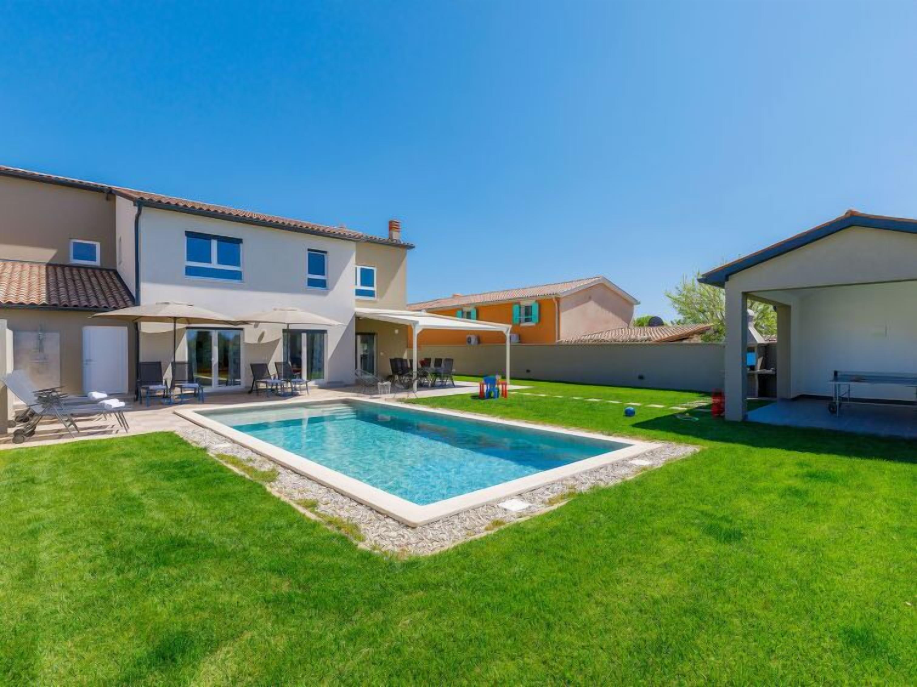 A residential property with a swimming pool, outdoor seating area, and a covered patio.