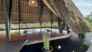 A thatched-roof structure with a wooden deck and a small pond with water lilies. - GDAS Bali Health and Wellness Resort (Ubud)