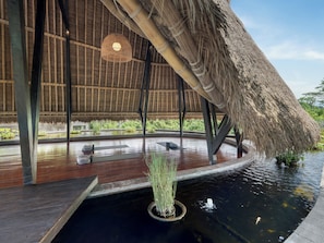 A thatched-roof structure with a wooden deck and a small pond with water lilies. - GDAS Bali Health and Wellness Resort (Ubud)