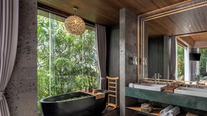A modern bathroom with a large bathtub, a round ottoman, and a large mirror. - GDAS Bali Health and Wellness Resort (Ubud)