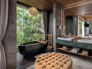 A modern bathroom with a large bathtub, a round ottoman, and a large mirror. - GDAS Bali Health and Wellness Resort (Ubud)