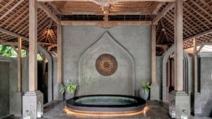 A spa area with a central hot tub, stone steps, and decorative wall elements. - GDAS Bali Health and Wellness Resort (Ubud)