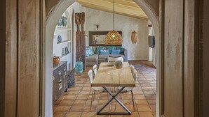 Un coin repas avec une table et des chaises en bois, un luminaire suspendu et un canapé avec des coussins.