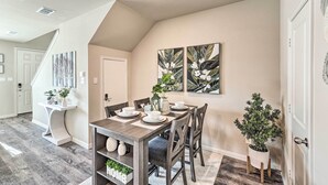 A dining area with a wooden table, chairs, and a potted plant. - Brand-New Townhome Near UNT/TWU & The Square! (Denton)