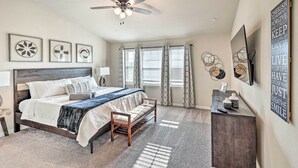 A bedroom with a bed, a bench, a desk, and a ceiling fan. - Brand-New Townhome Near UNT/TWU & The Square! (Denton)