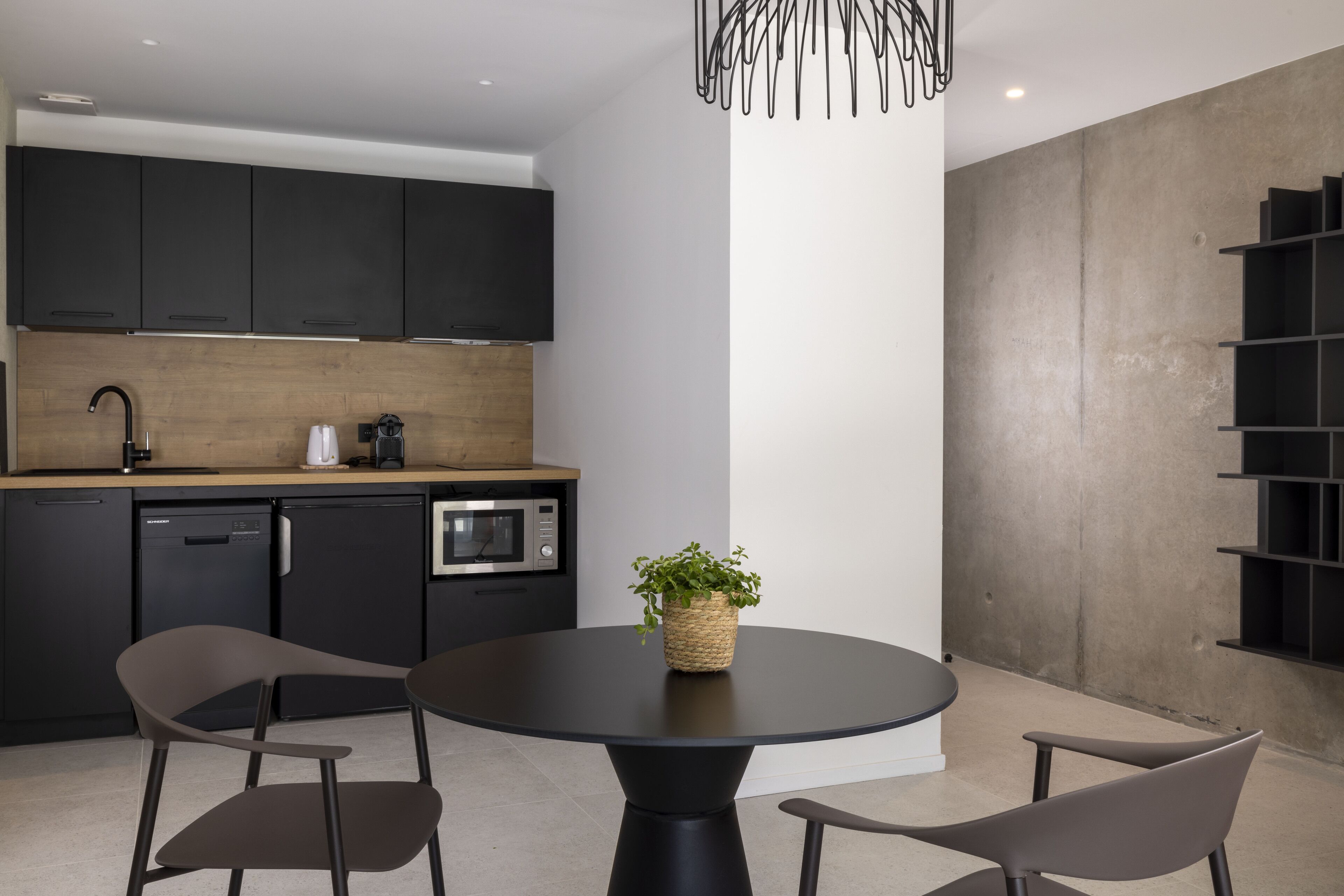 A modern kitchen with dark cabinets, a round black table, and two chairs.