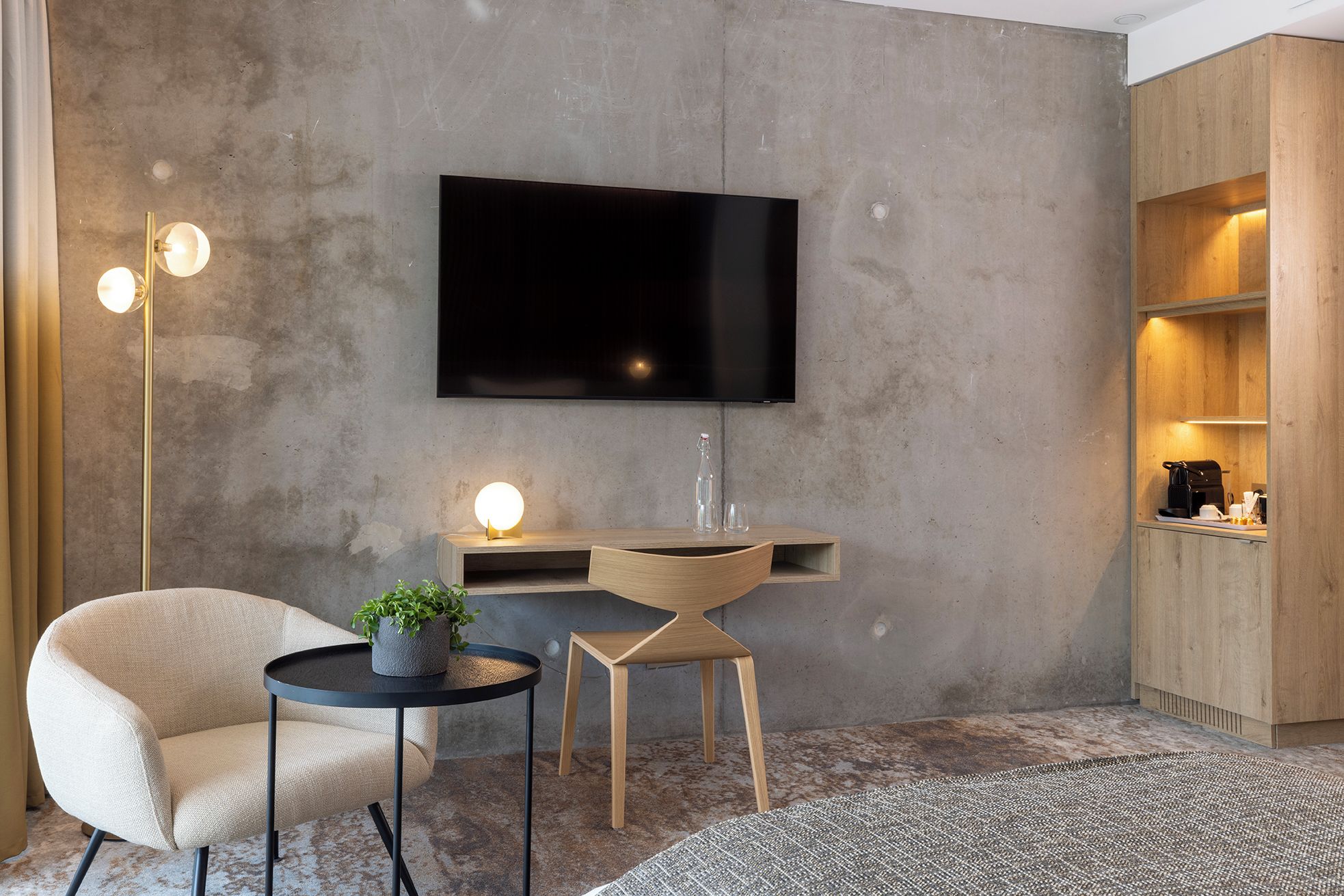 Un salon moderne avec un téléviseur à écran plat, une table ronde ornée d’une plante, un canapé et une machine à café.