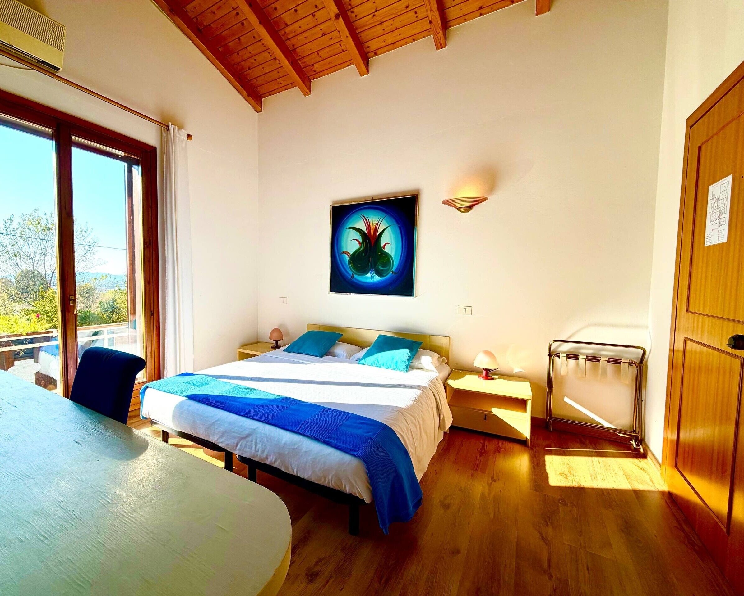 Une chambre à coucher avec un lit, des tables de chevet, une lampe, un radiateur et une fenêtre donnant sur un beau paysage.