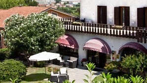 A building with a courtyard, outdoor seating, and a view of the surrounding landscape. - Hotel New Genziana (Altavilla Vicentina)