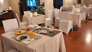 A dining area with tables set for breakfast, including plates of fruit, pastries, and beverages. - Hotel New Genziana (Altavilla Vicentina)