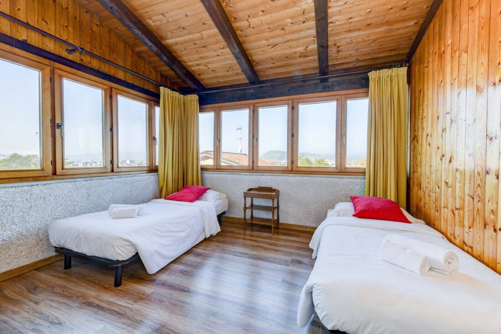 Ein Zimmer mit zwei Betten, Holzwänden und großen Fenstern.