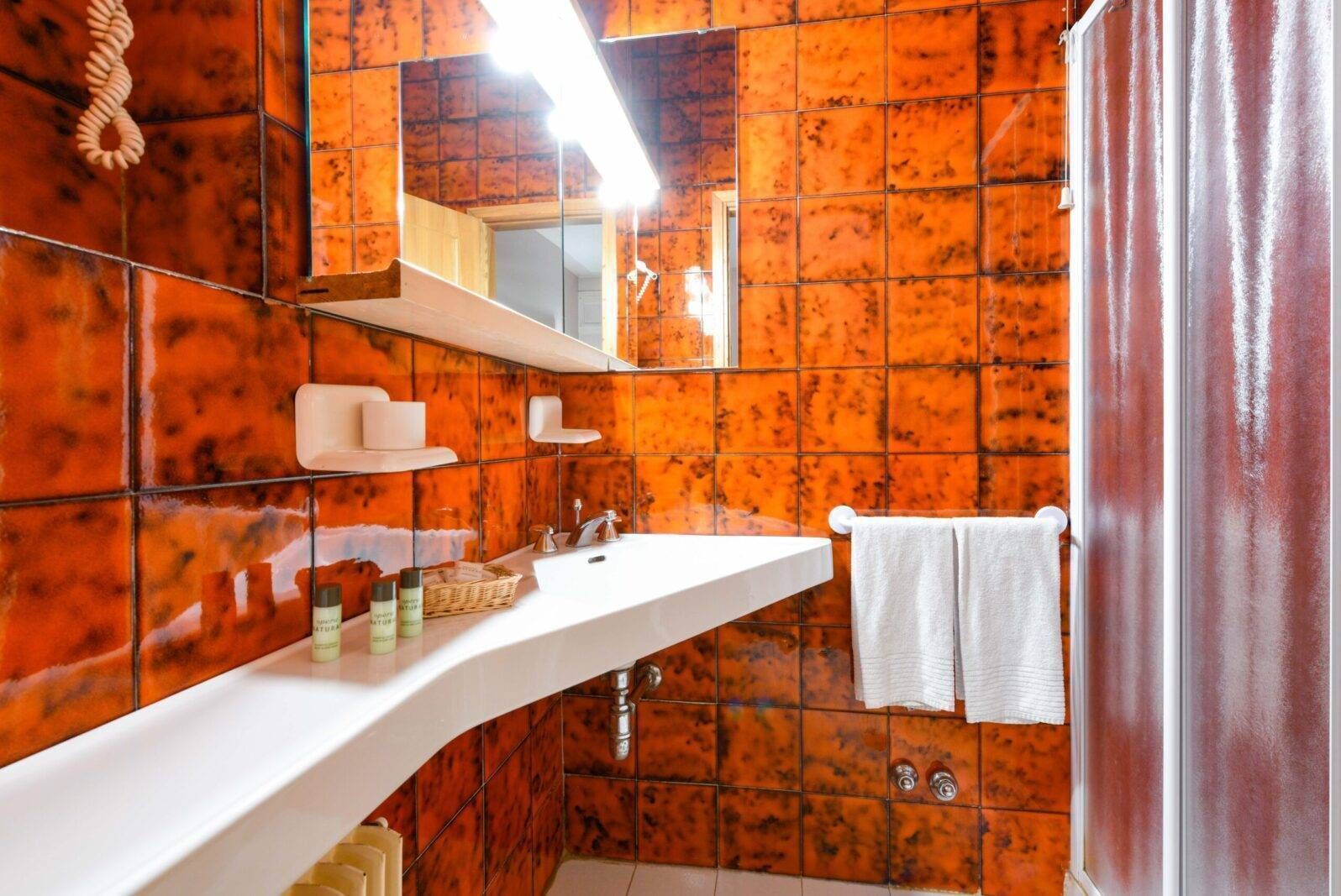 Een badkamer met een wit wastafelmeubel, spiegel en handdoekhouder.