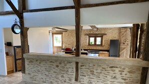 A rustic kitchen with exposed stone walls, wooden beams, and a stone counter. - Converted barn/gergergerie in the countryside. (Castelner)