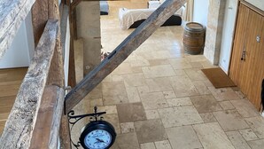 A rustic room with exposed wooden beams, a bed, a wooden barrel, and a clock on the wall. - Converted barn/gergergerie in the countryside. (Castelner)