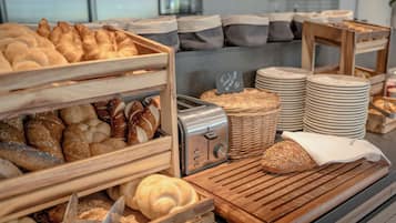 Une vitrine de boulangerie présentant diverses sortes de pains et de viennoiseries, un grille-pain et des assiettes empilées.