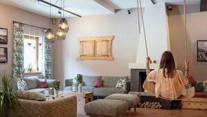 A cozy living room with a swing chair, a fireplace, and a rustic wooden cabinet. - AlpenParks Ferienresort Rehrenberg (Viehhofen)