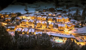 Une station de ski enneigée comprenant plusieurs bâtiments, une piscine et un télésiège.