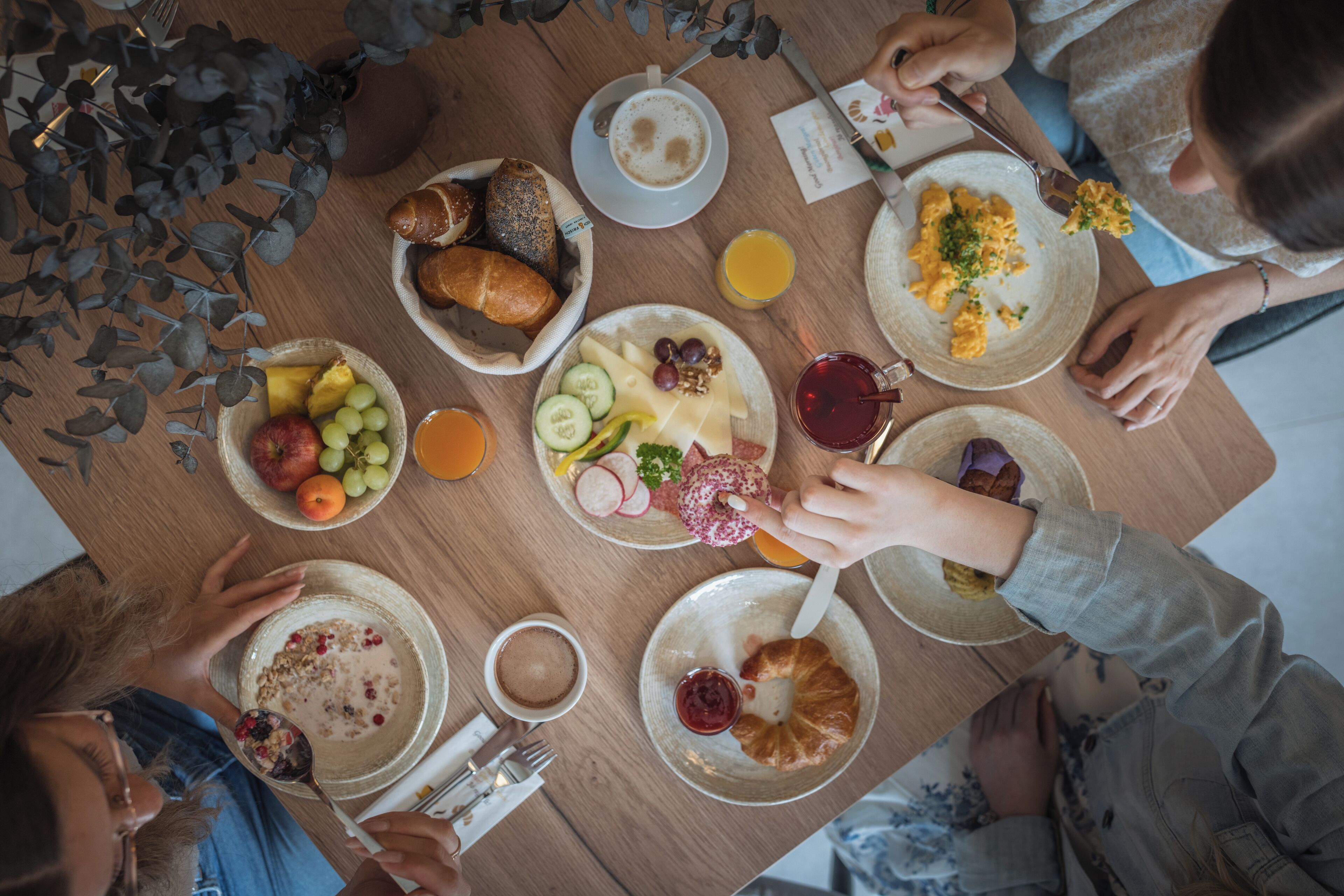 A breakfast setting with various food items and beverages on a wooden table.