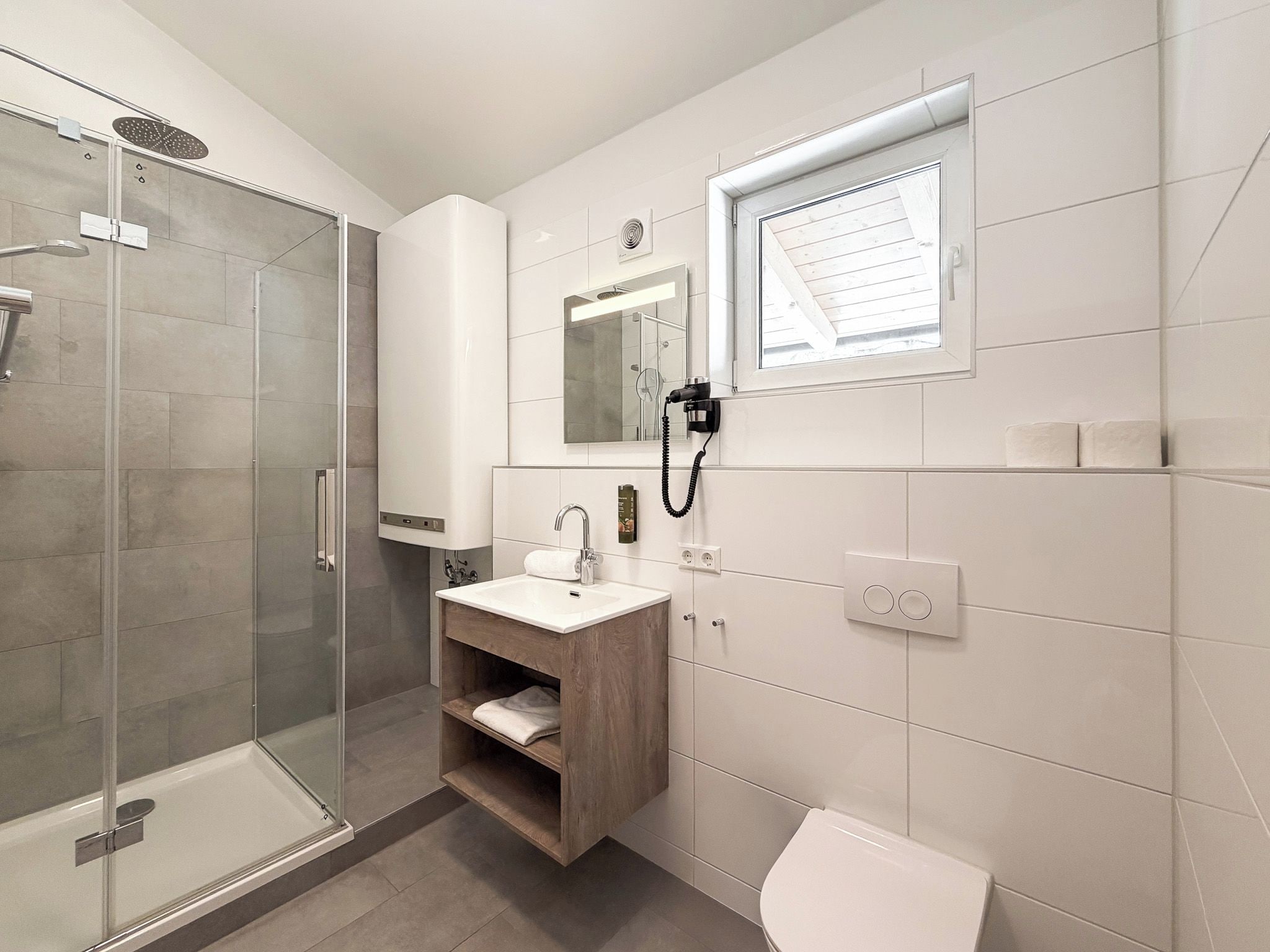A modern bathroom with a glass shower enclosure, a wooden vanity with a sink, and a toilet.