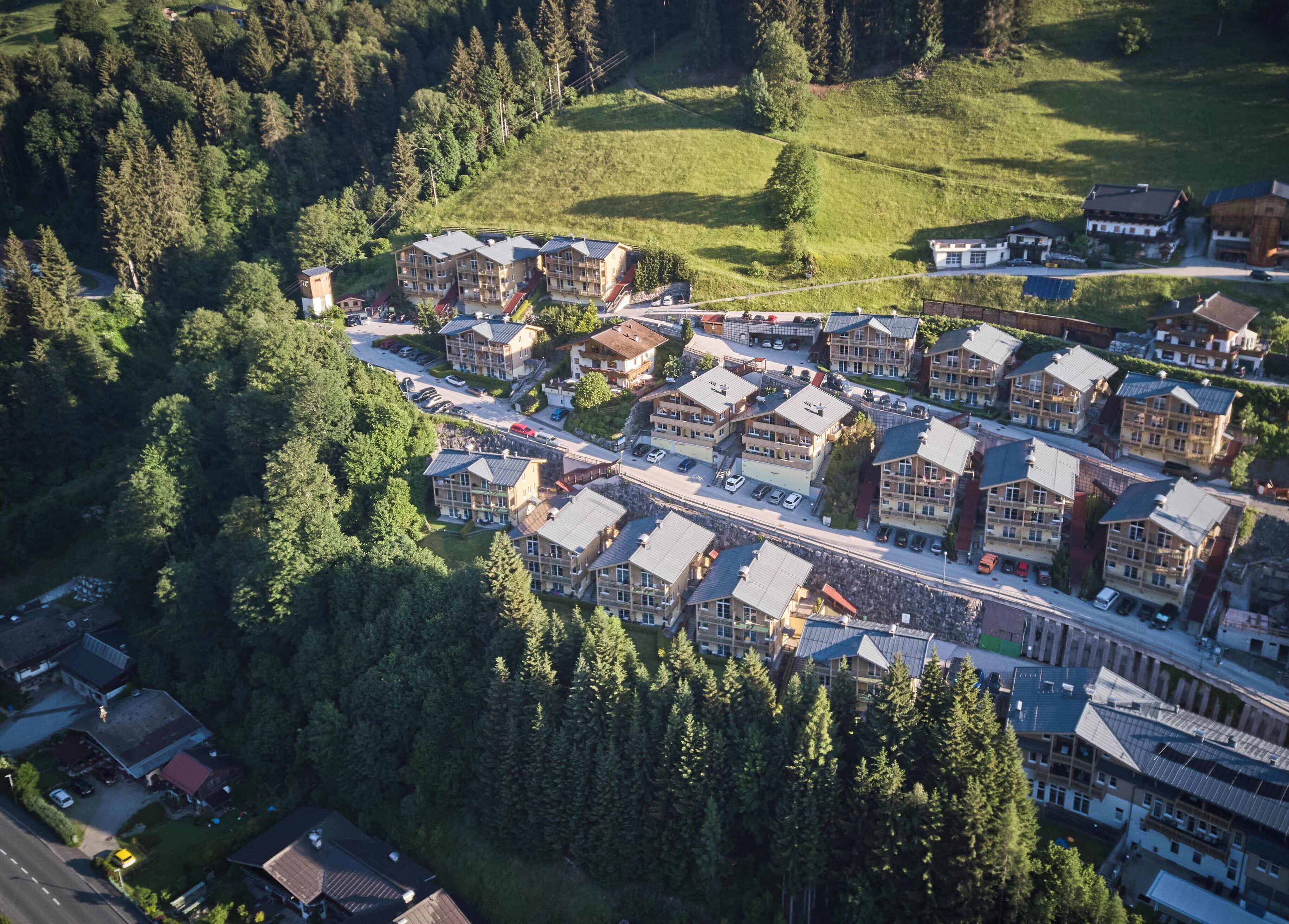 An aerial view of a residential area with multiple apartment buildings, roads, and surrounding greenery.