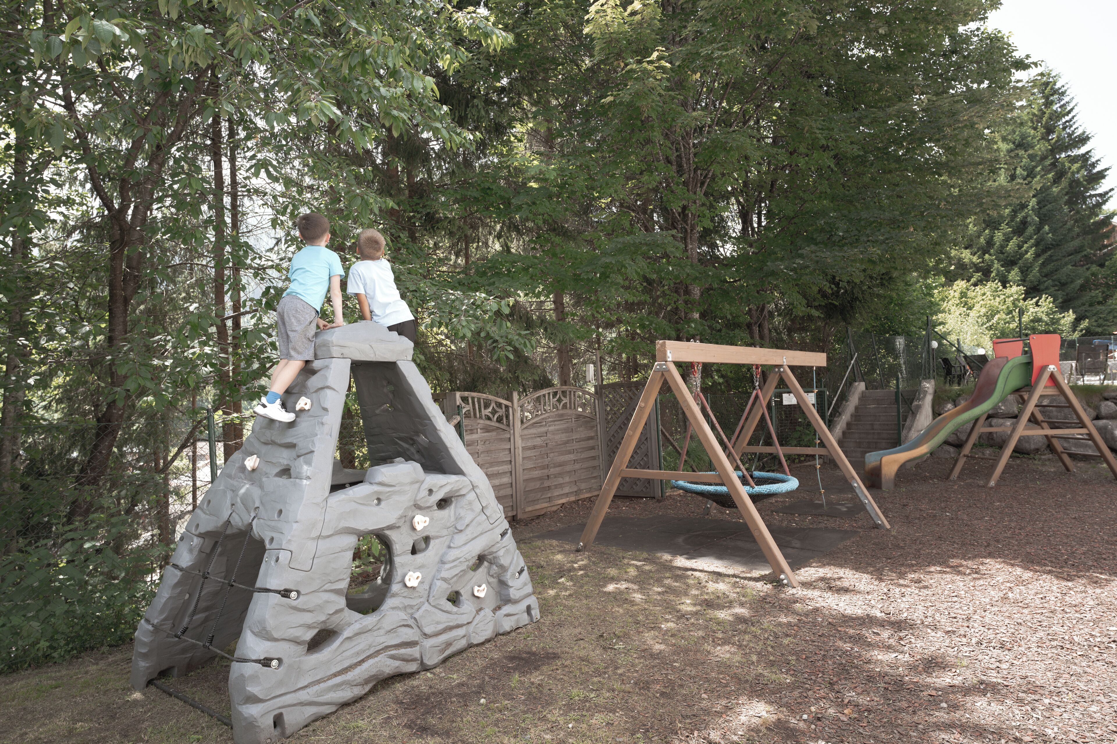 A playground with a climbing structure, a swing set, and a slide.
