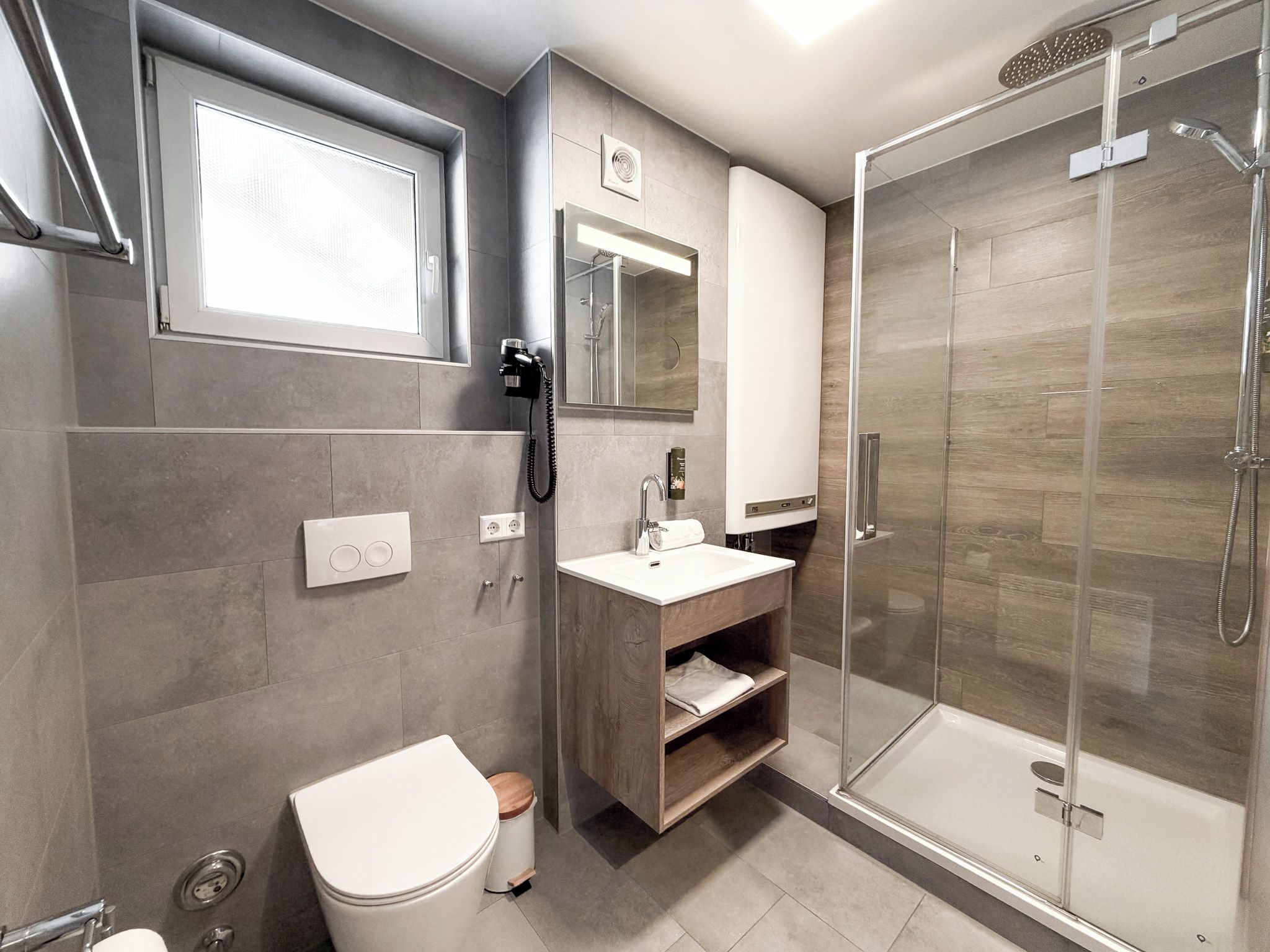 Un baño moderno con inodoro, lavabo, espejo y cabina de ducha de vidrio.