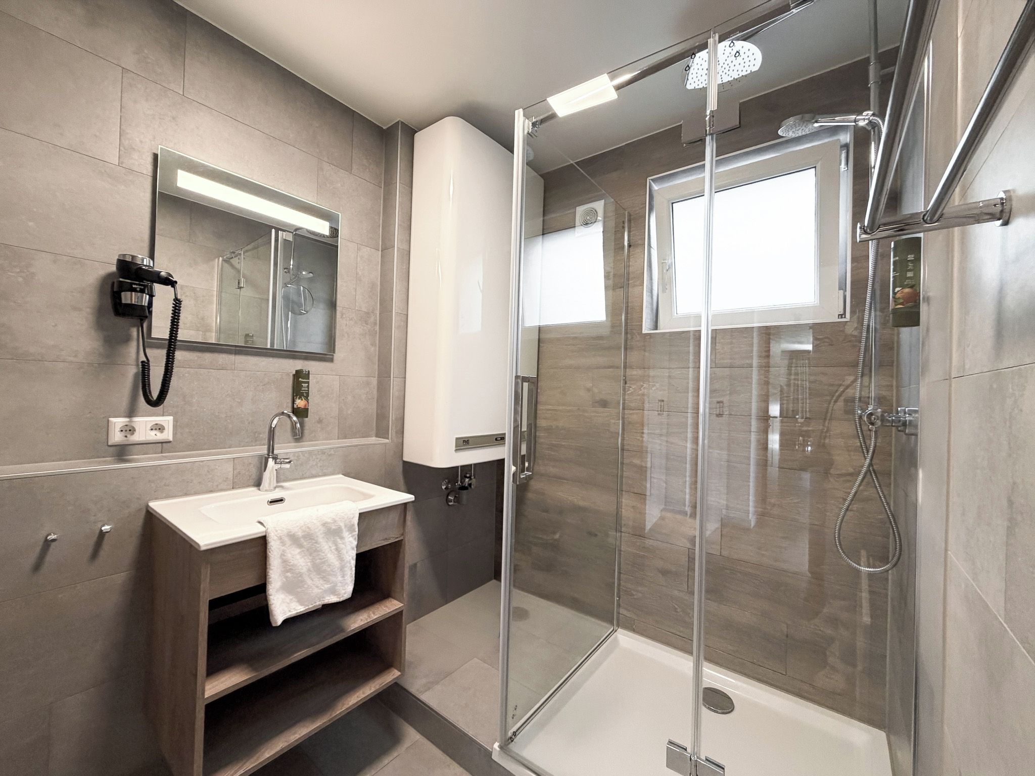 A modern bathroom with a glass-enclosed shower, a vanity with a sink, and a mirror above the vanity.