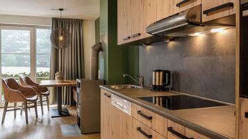 Una cocina moderna con armarios de madera, un lavamanos de acero inoxidable y una estufa integrada. Hay una zona de comedor con sillas y una mesa.