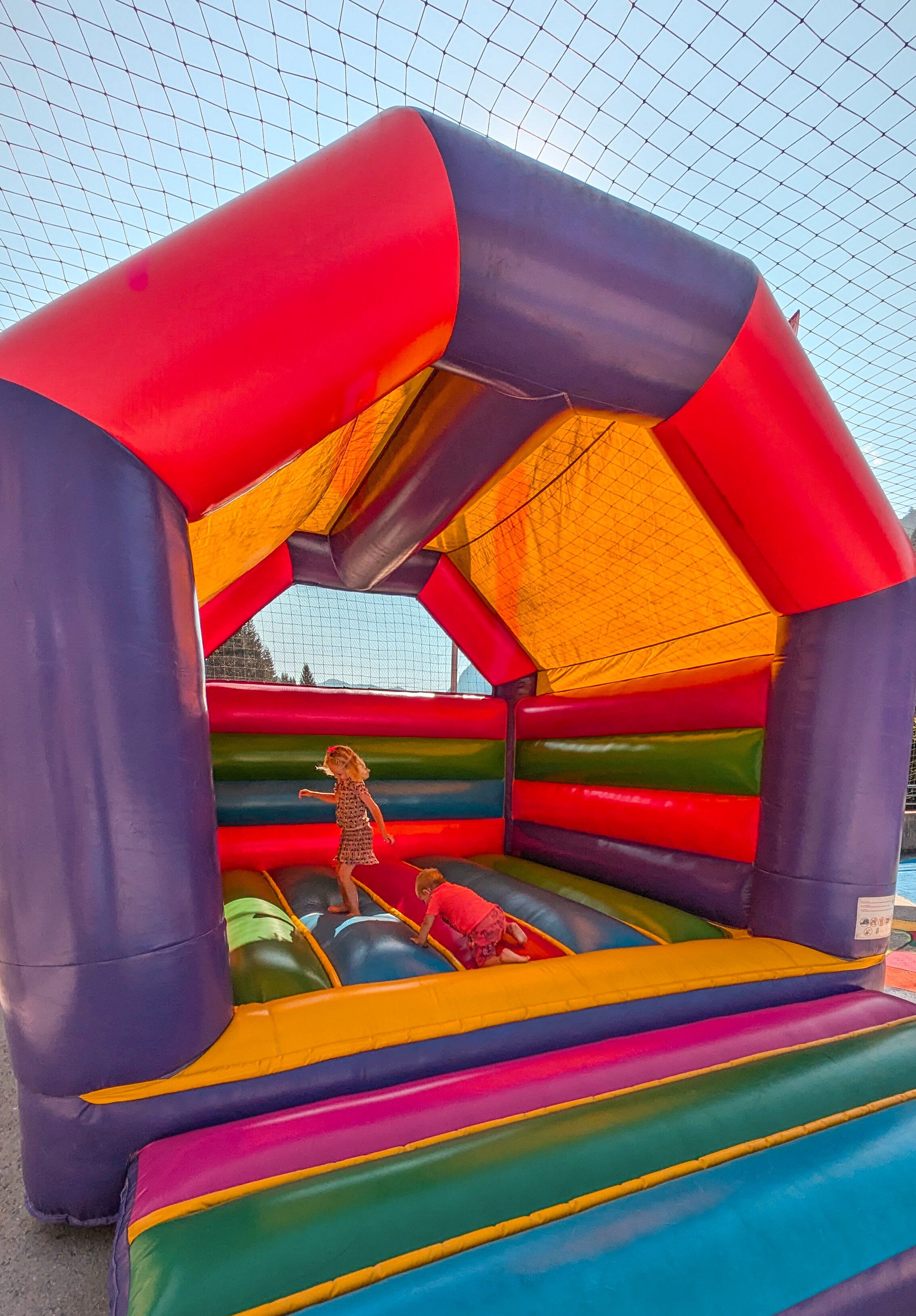 Un castillo inflable colorido con techo de malla.