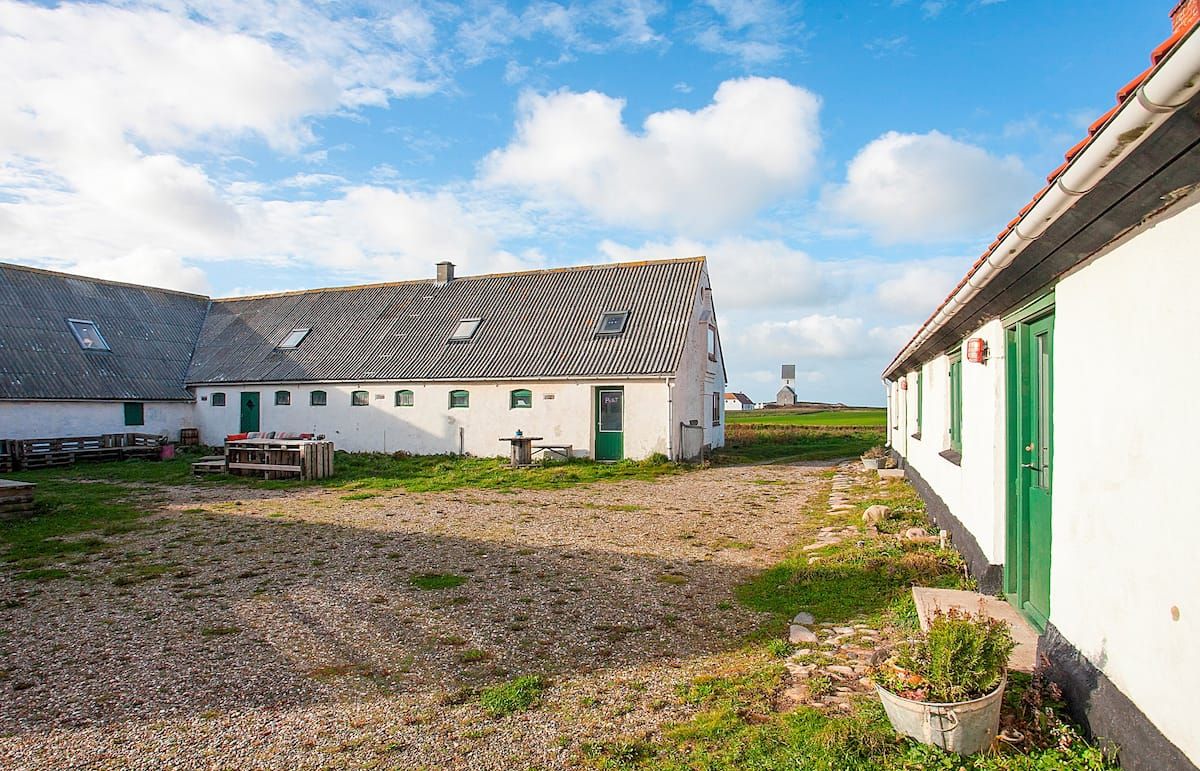 A courtyard with buildings, gravel ground, and a clear sky.