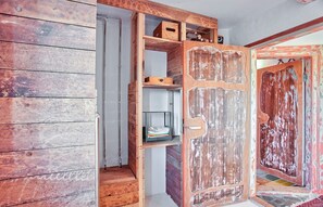 A room with a wooden door, built-in shelves, and a staircase.