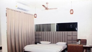 Un dormitorio con una cama, cortinas, ventilador de techo y un comedor con mesa y sillas.