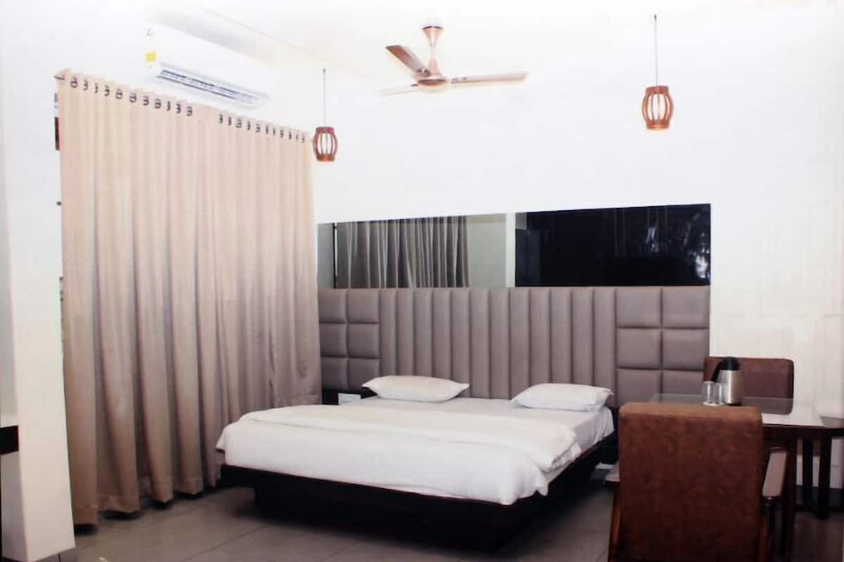 A bedroom with a bed, curtains, a ceiling fan, and a dining area with a table and chairs.