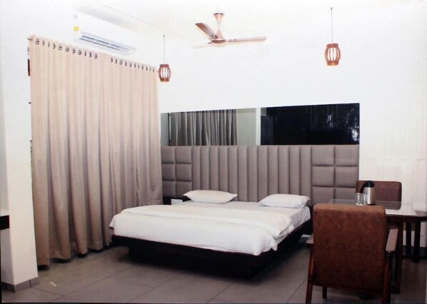 Un dormitorio con una cama, cortinas, ventilador de techo y un comedor con mesa y sillas.
