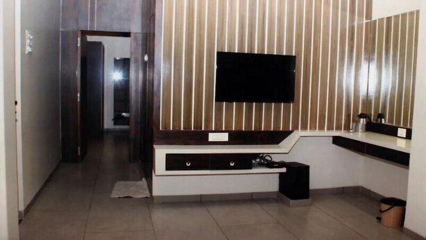 Un baño moderno con un espejo grande, un televisor de pantalla plana montado en una pared de paneles de madera y un tocador empotrado con lavamanos.