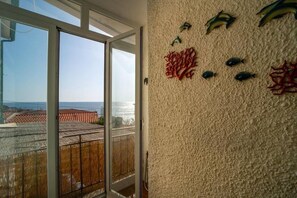 Una habitación con un ventanal grande, un muro con textura y motivos de peces, y vista a la costa.