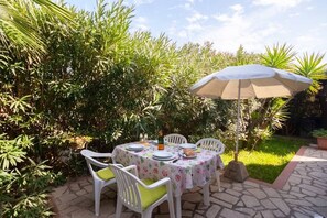 Eine Terrasse im Freien mit einem Essbereich, umgeben von üppigem Grün.