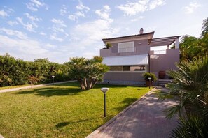 Ein modernes, zweistöckiges Haus mit gepflegtem Rasen, einem Weg zum Eingang und blauem Himmel.