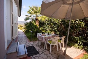 An outdoor patio with a table and chairs, a large umbrella, and a view of a mountain.