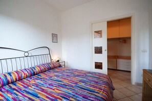 Une chambre à coucher comprenant un lit, une table de chevet et une porte donnant sur une salle de bain.