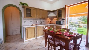 Una cocina con armarios de madera, una mesa de comedor con sillas y vistas al exterior.