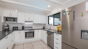 A modern kitchen with white cabinets, stainless steel appliances, and a large refrigerator.