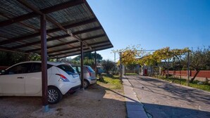 A covered parking area with two cars parked under a metal roof. - Aricipelgo - Ponza apartment (Marina di Campo)