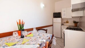 Une petite cuisine équipée d’un réfrigérateur, d’une cuisinière et d’un four à micro-ondes. On y trouve une table à manger avec des chaises et une nappe.