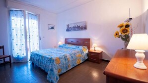 A bedroom with a bed, a nightstand, a lamp, a chair, and a window with curtains.